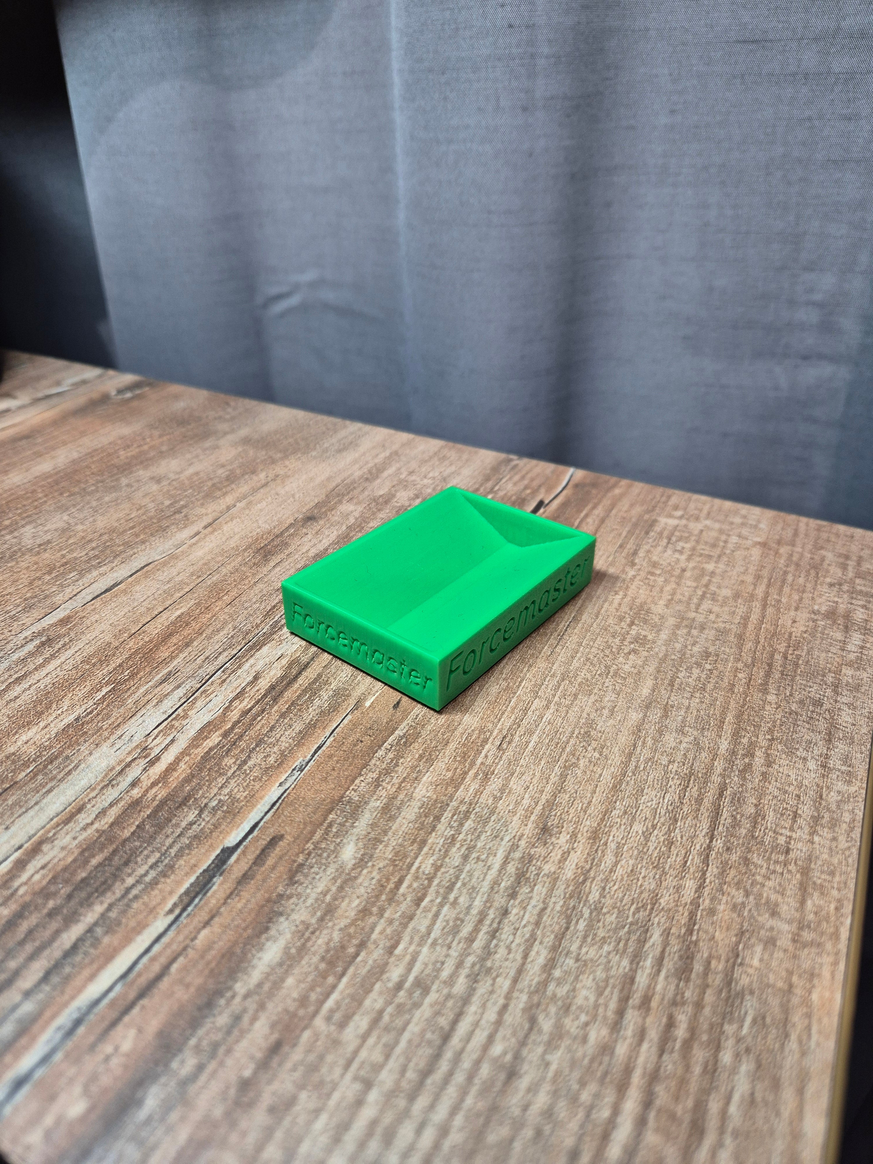 Druk 3D Forcemaster: zielona blokada pod kółka fotela obrotowego na drewnianym biurku. Produkt do stabilizacji krzesła w simracingu.